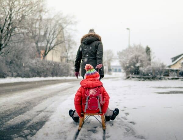 A Mother Carrying her Child on a Sleigh - Through a Snow Covered Street - Marcel Walter - From Unsplash