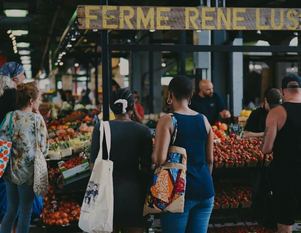 Women in Front of a Fruit and Vegetable Stand - at the Jean-Talon Market - Moise M - From Unsplash