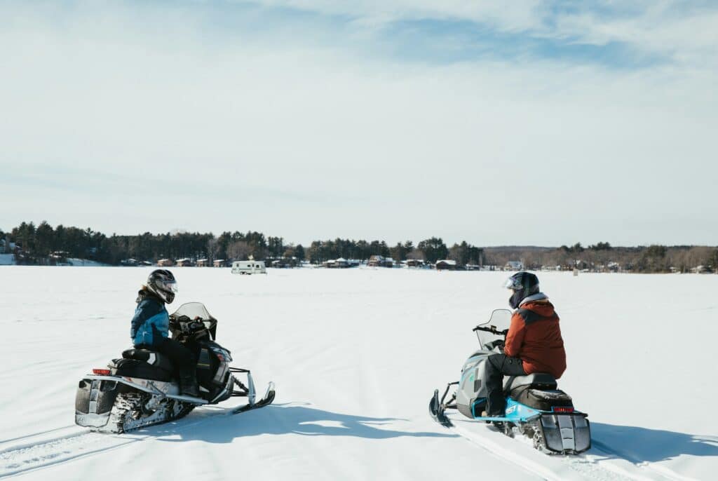Two People with Snowmobiles - on a Frozen Lake - Ethan Walsweer - from Unsplash